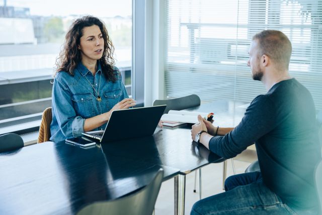 Witte vrouw met donker haar in gesprek met witte man